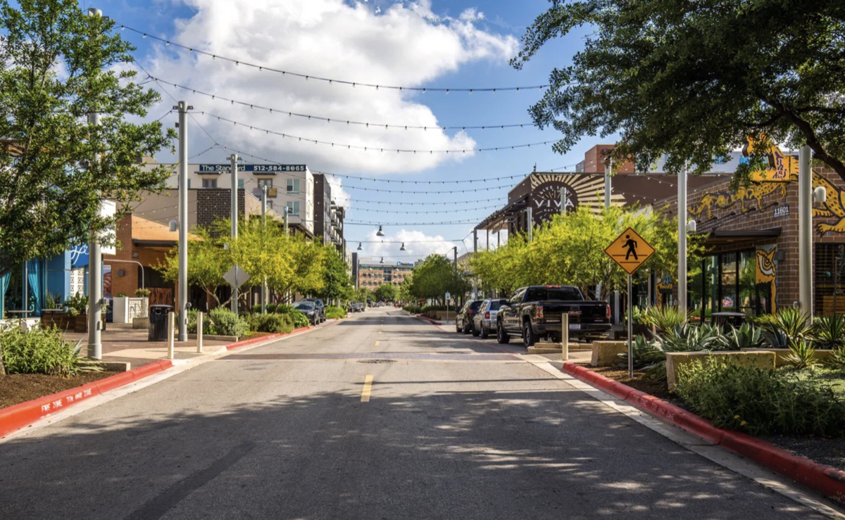 Tree-lined street in The Domain with shops and overhead string lights
