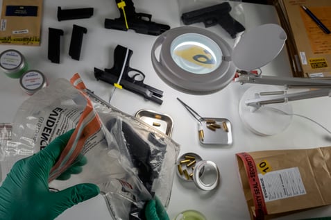 police-scientist-pulls-firearm-evidence-out-of-bag-2023-11-27-05-37-16-utc